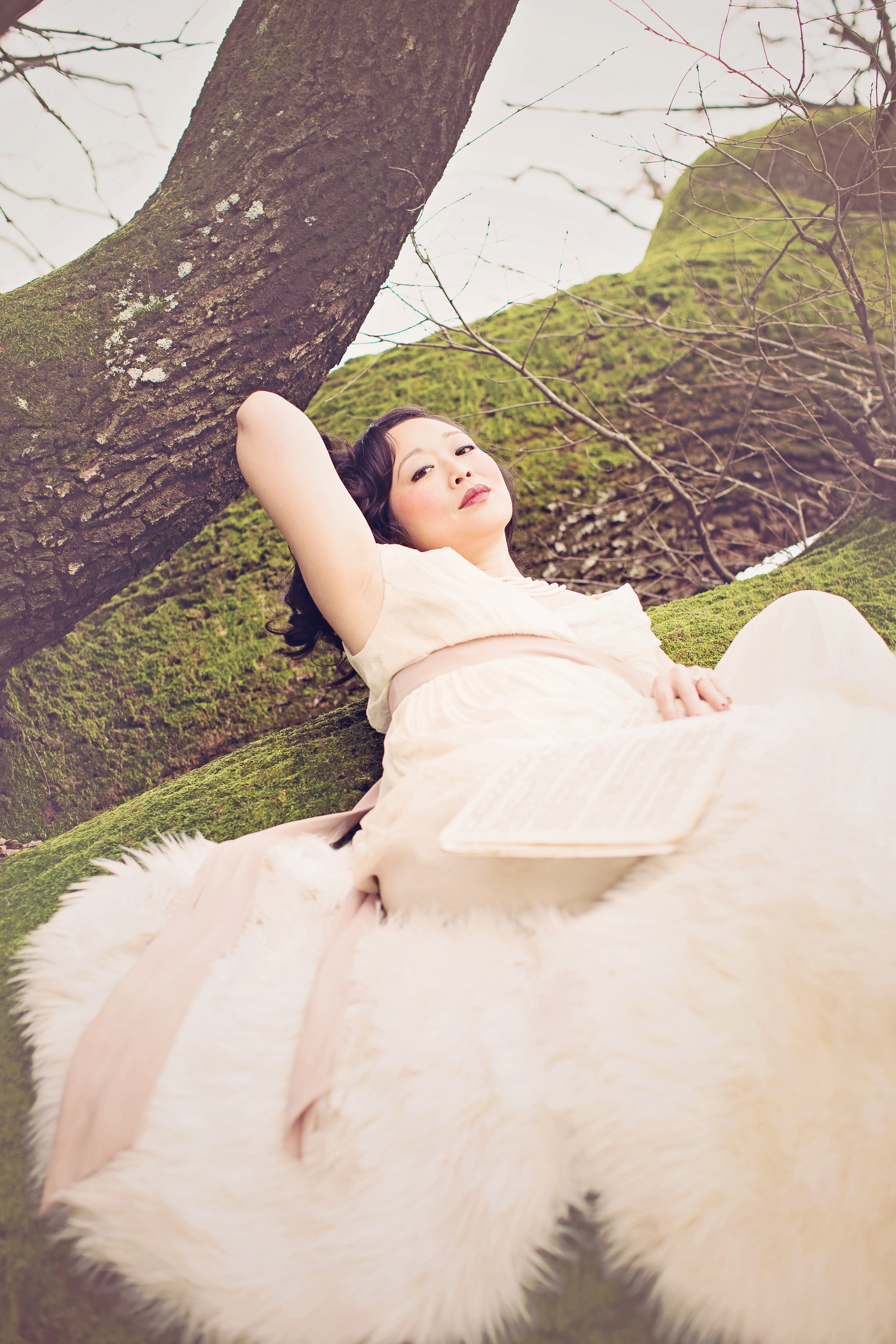 Charlene Chi lying on a 600 year old tree with sheet music